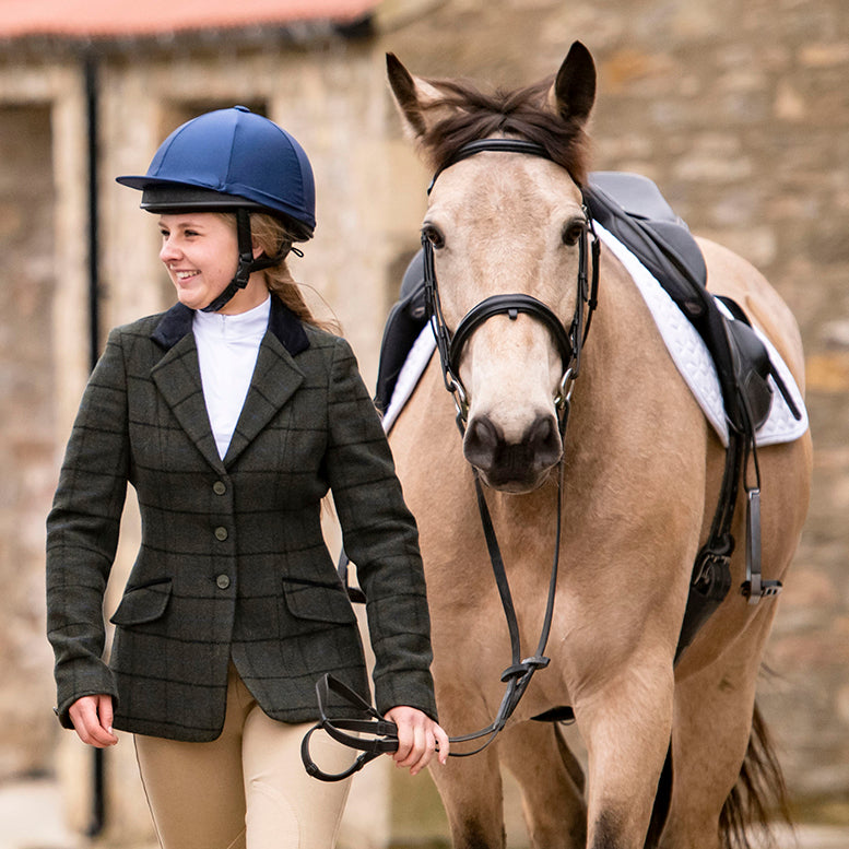 Woman in tweed competition gear with a dun horse