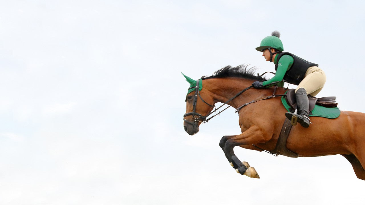 Horse jumping with rider, wearing Hy Equestrian clothing and saddlery