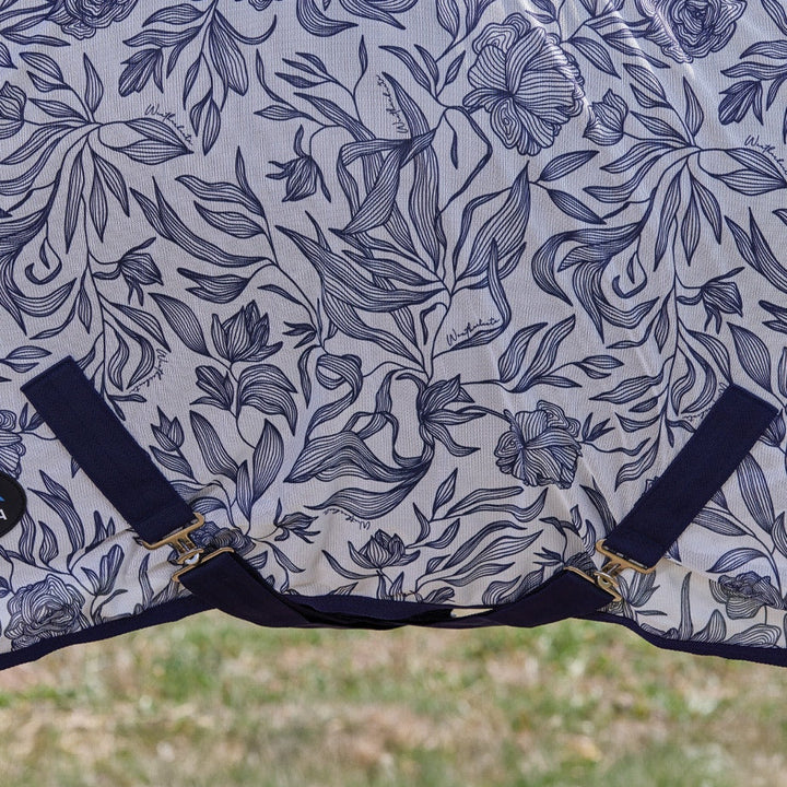 Floral patterned horse blanket with straps on a grassy background