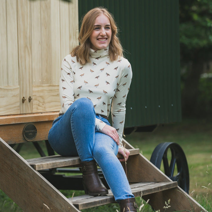 Woman sitting on a wooden ladder in front of a shepherd's hut.