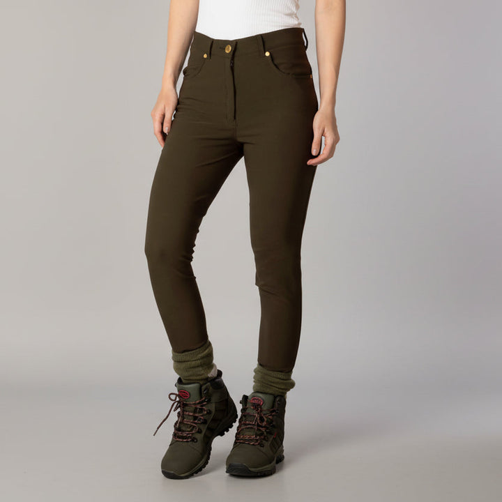 Person wearing olive green pants and hiking boots on a gray background