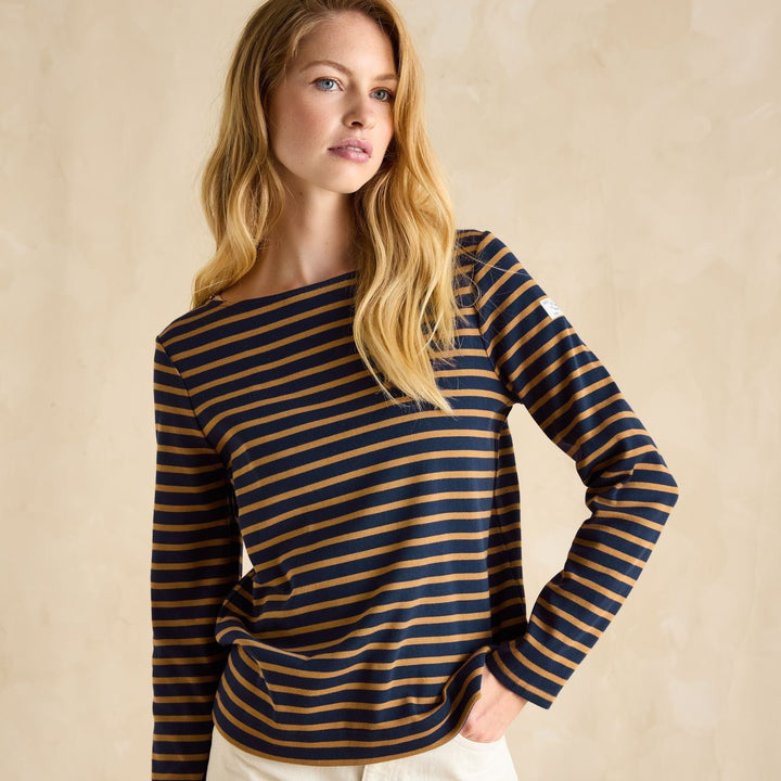 Woman wearing a striped long-sleeve top against a beige background