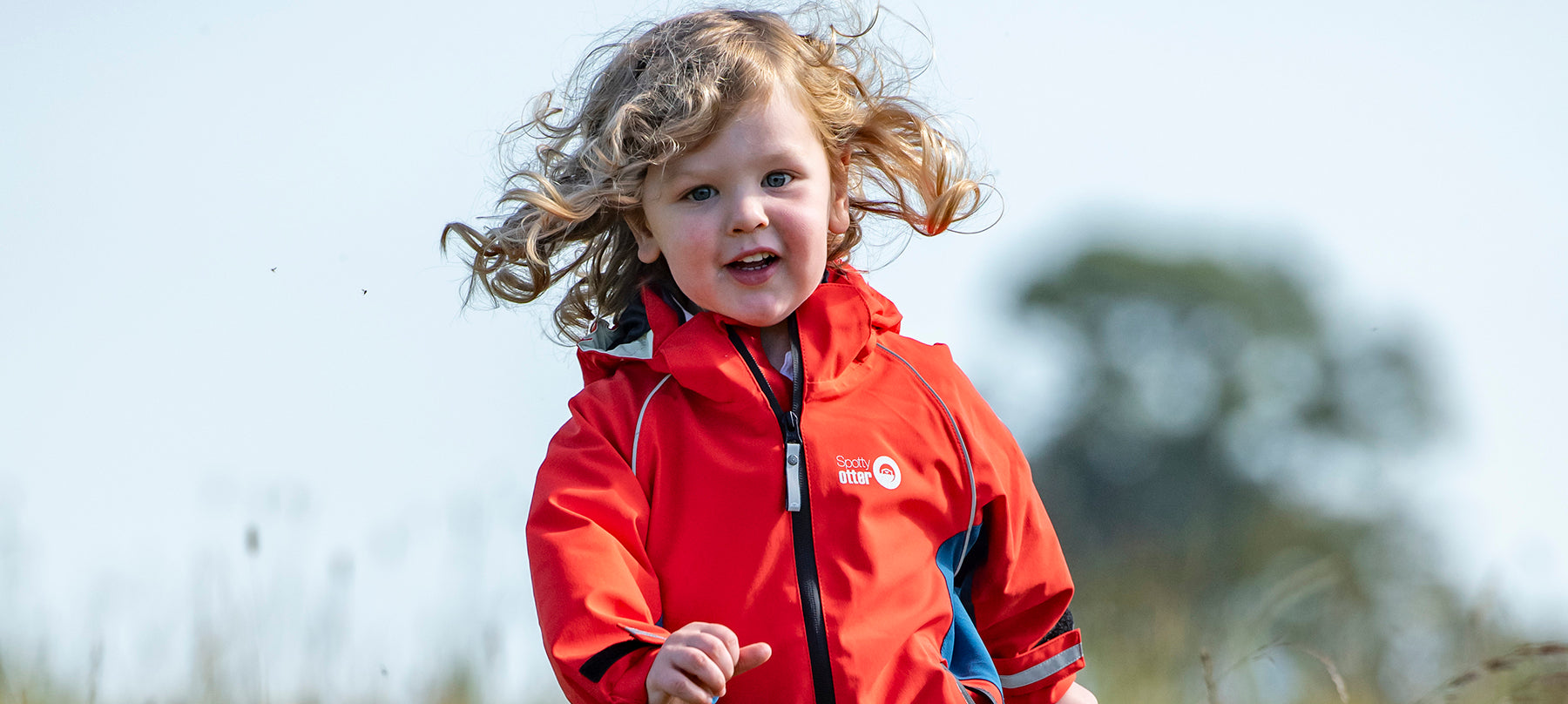 A boy running in a field in a red jacket