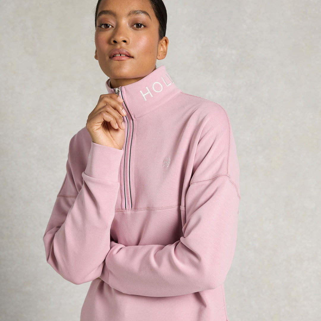 Woman wearing a pink pullover with a zipper on a light gray background