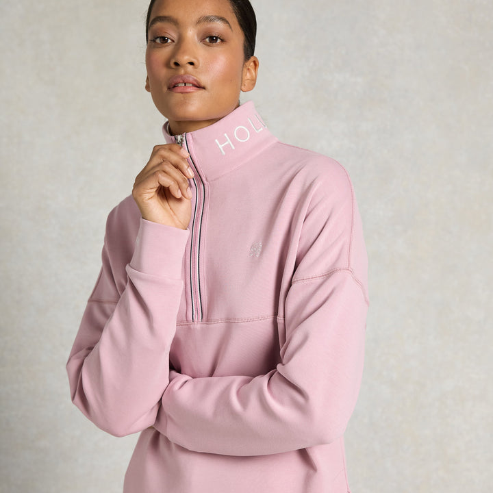 Woman wearing a pink pullover with a zipper on a light gray background