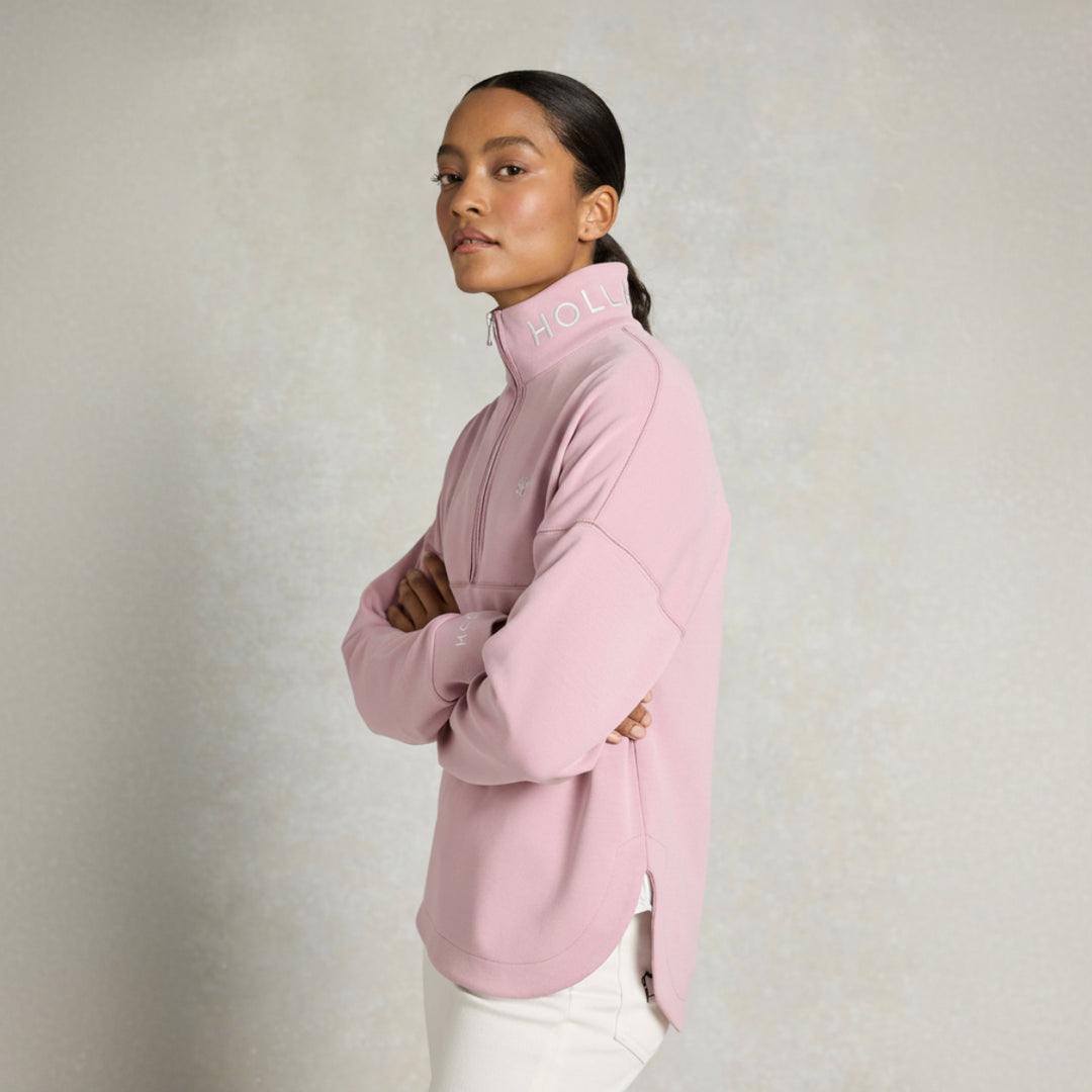 Woman wearing a pink jumper with 'HOLLAND COOPER' branding on a light background