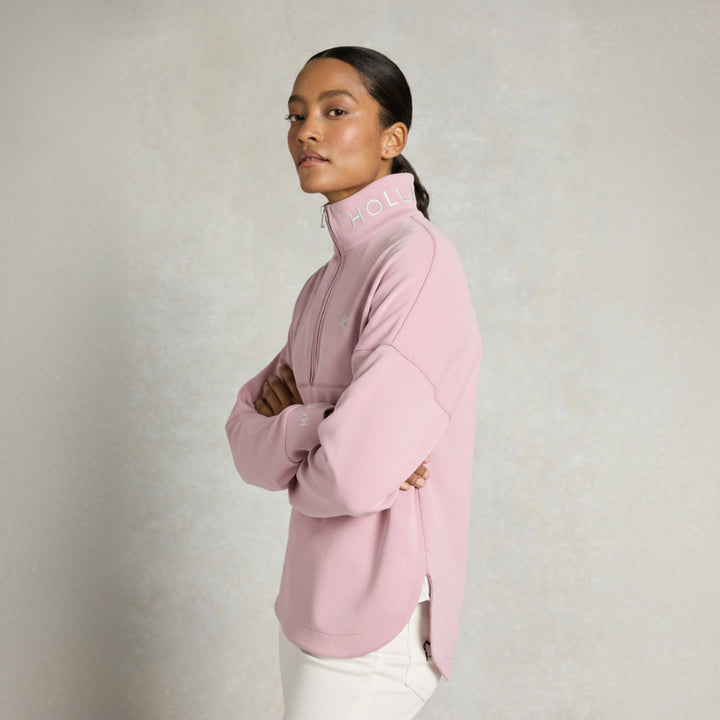 Woman wearing a pink jumper with 'HOLLAND COOPER' branding on a light background
