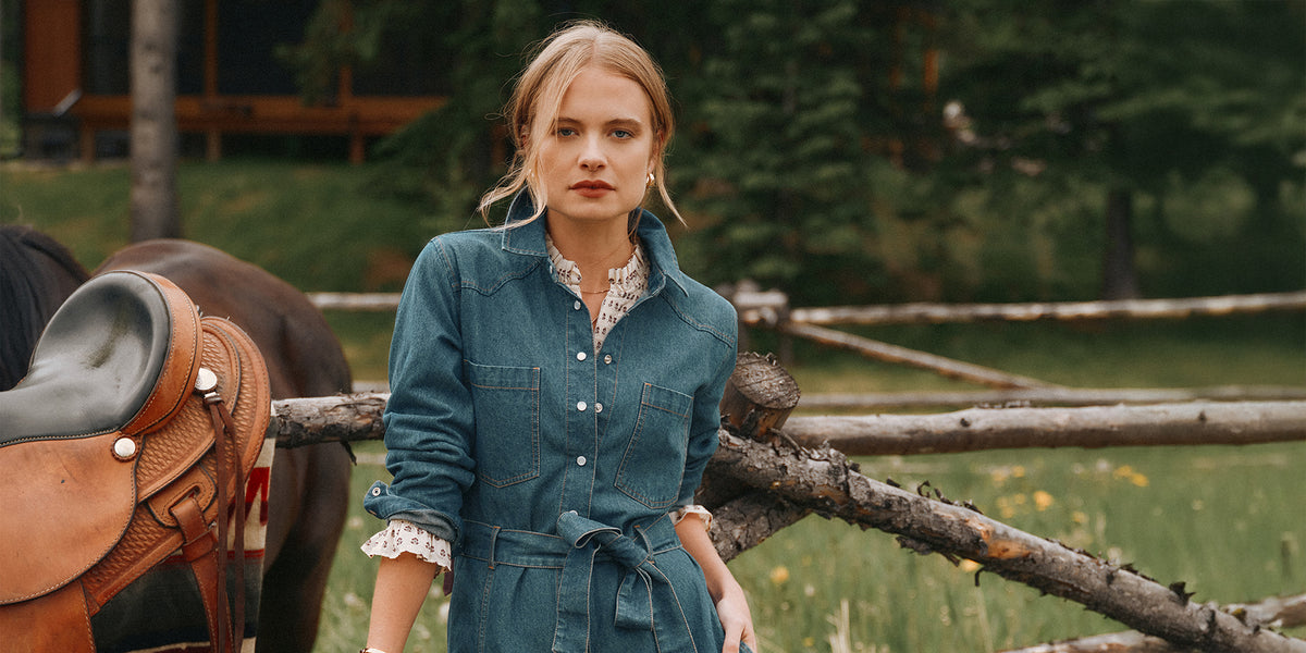 Woman in a field leaning against a fence wearing new Joules clothing