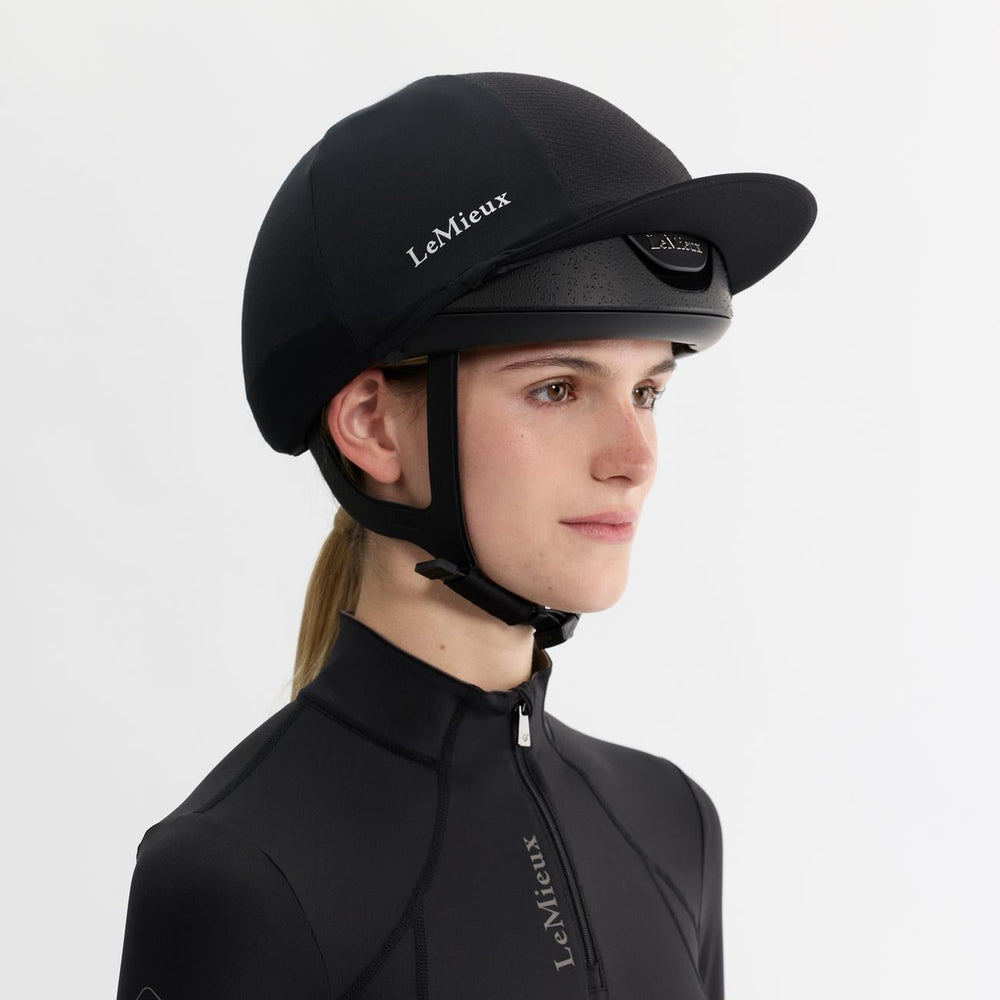 Person wearing a black equestrian helmet and jacket with 'LeMieux' branding on a white background