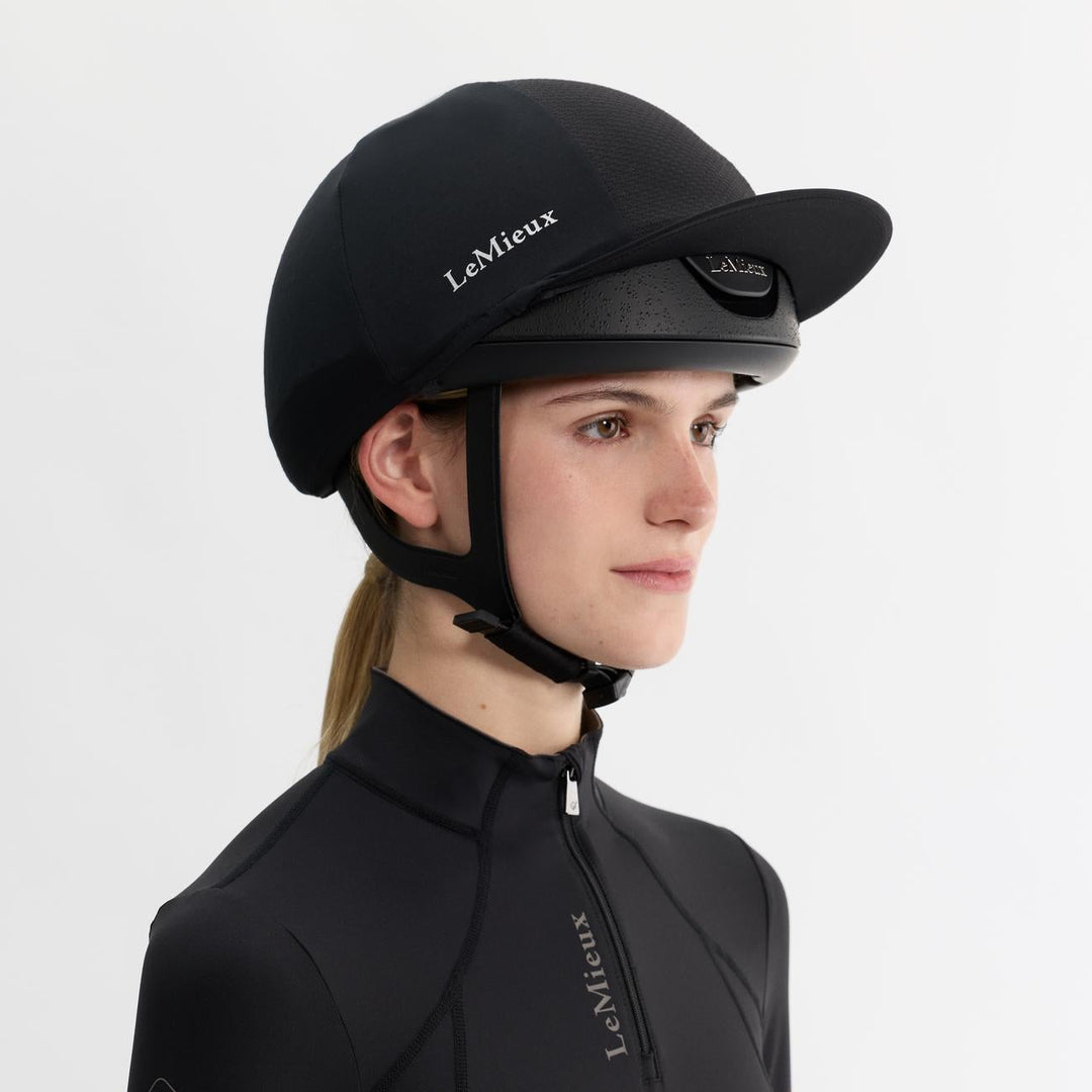 Person wearing a black equestrian helmet and jacket with 'LeMieux' branding on a white background