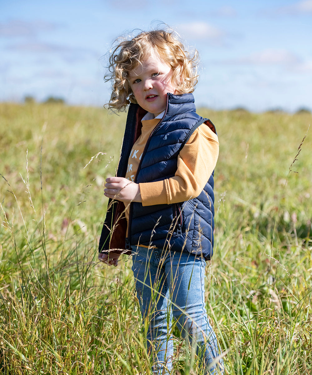 Kid in Joules clothing stood in a field