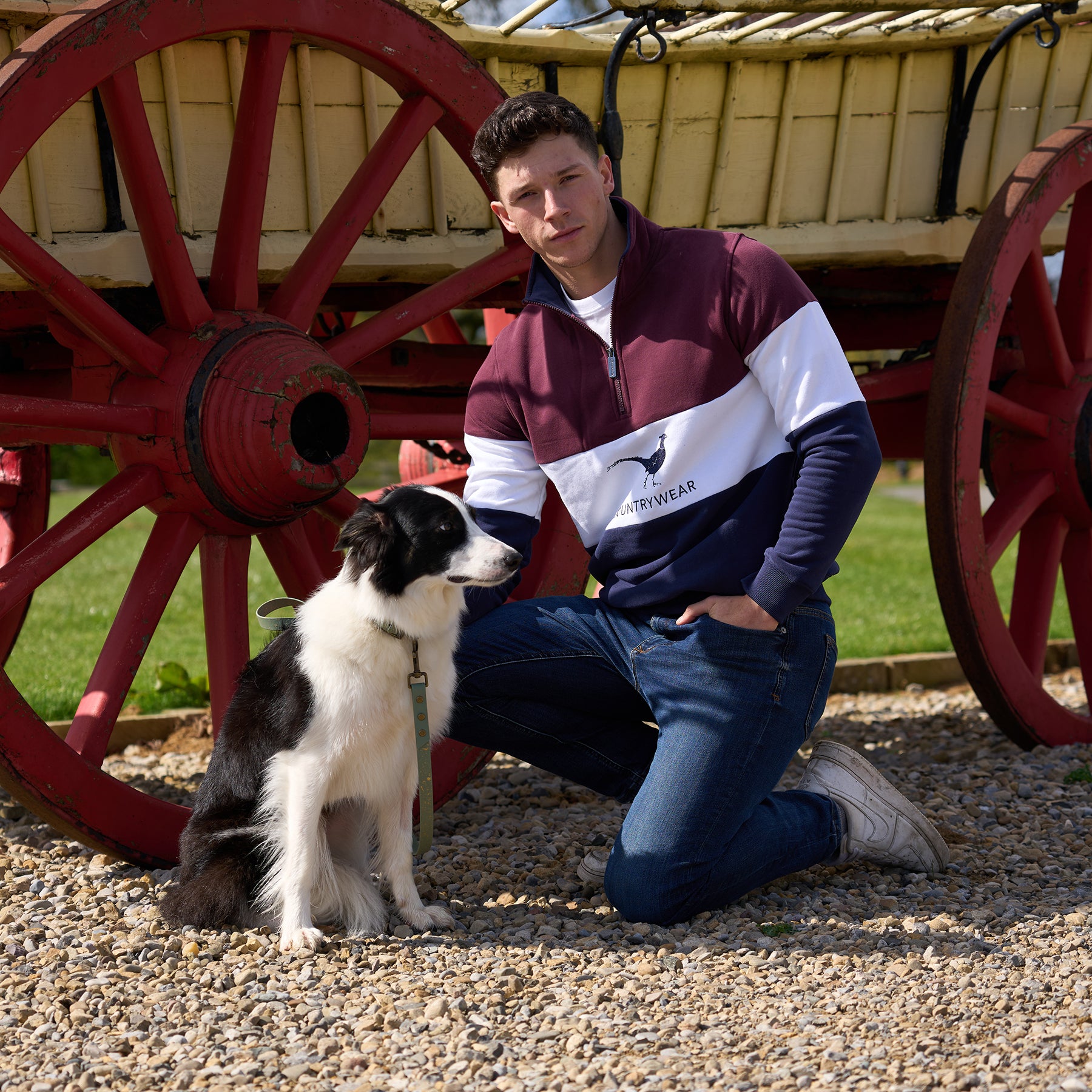 Man kneeling down by a wagon with a dog
