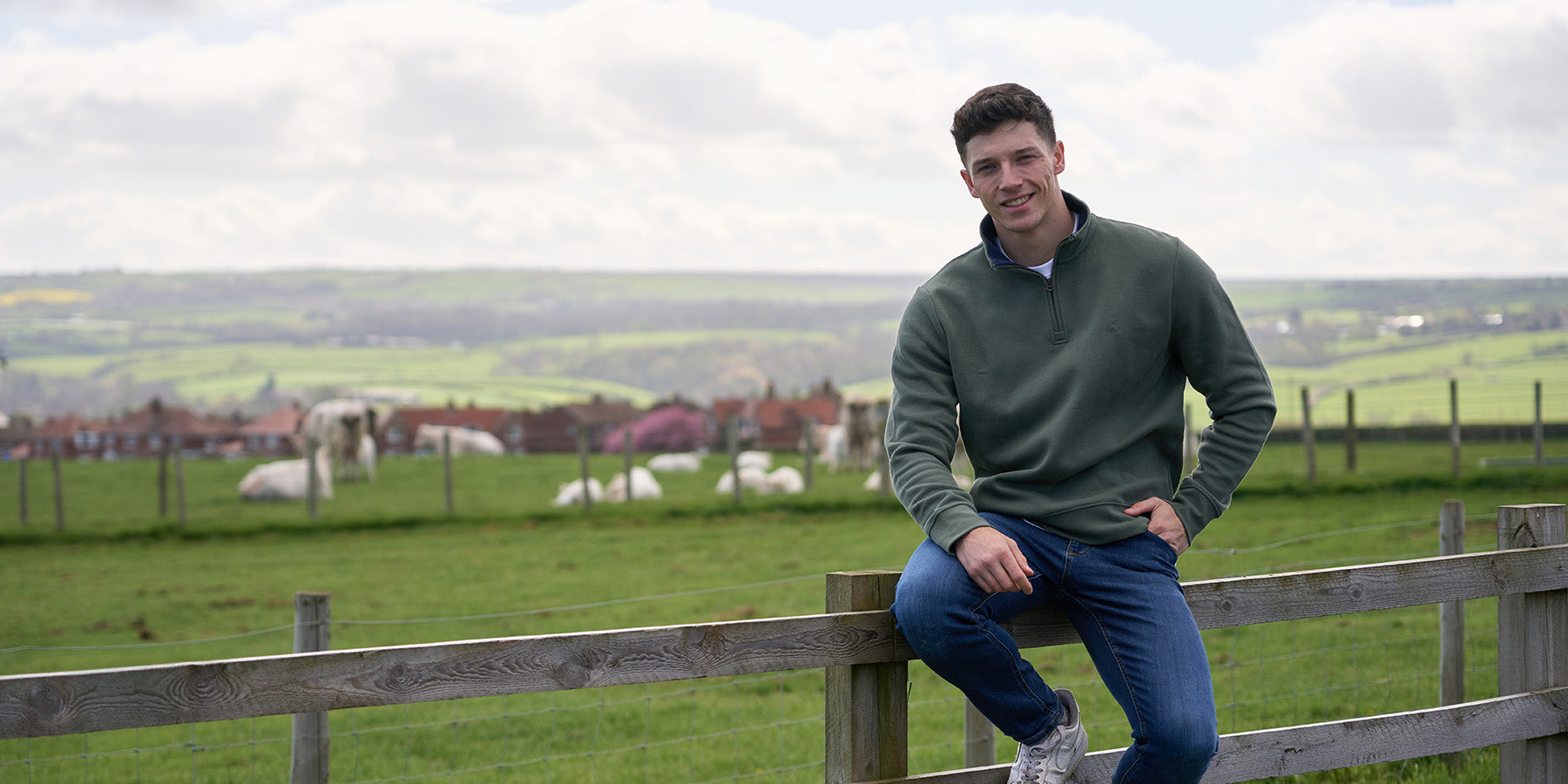 Man sat on a fence wearing Joules clothing