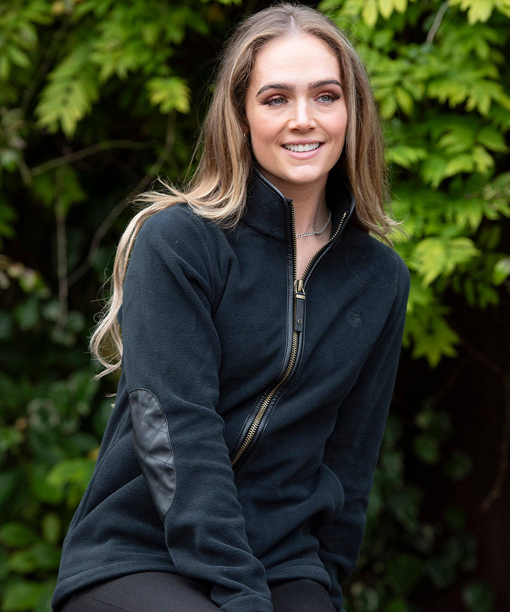 Woman sat on a fence wearing a Holland Cooper fleece jacket