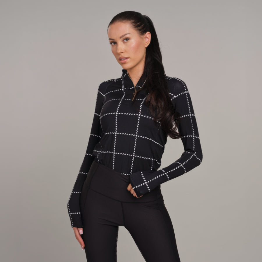 Woman wearing a black and white checkered baselayer against a gray background