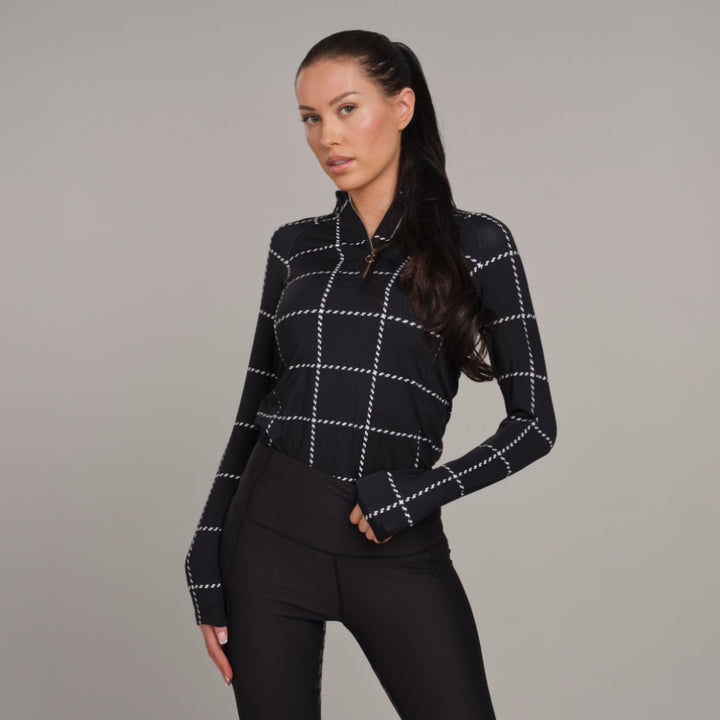 Woman wearing a black and white checkered baselayer against a gray background