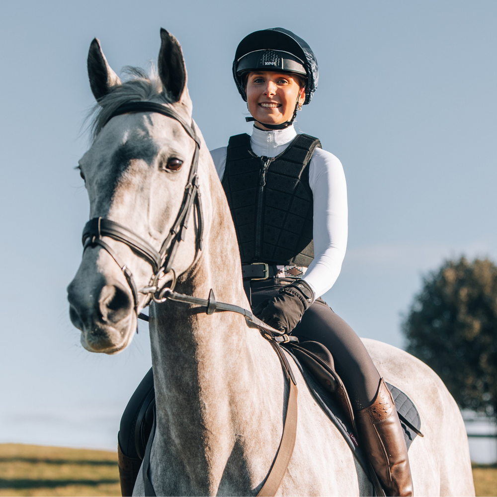 Person riding a horse in an outdoor setting with a clear sky
