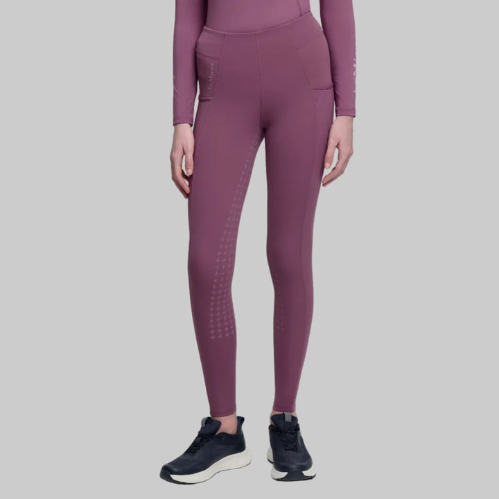 Person wearing purple athletic riding leggings and top on a white background